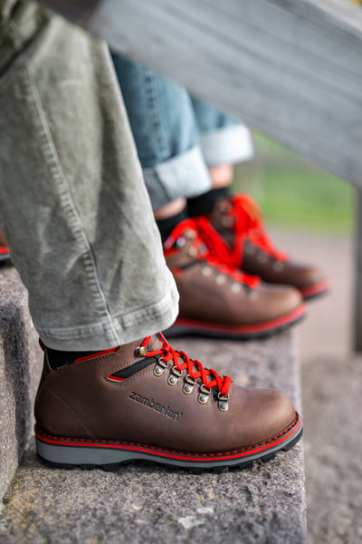 A close up of a person sitting on outdoor stairs wearing Zamberlan Toblach GTX men's hiking and lifestyle boots. 