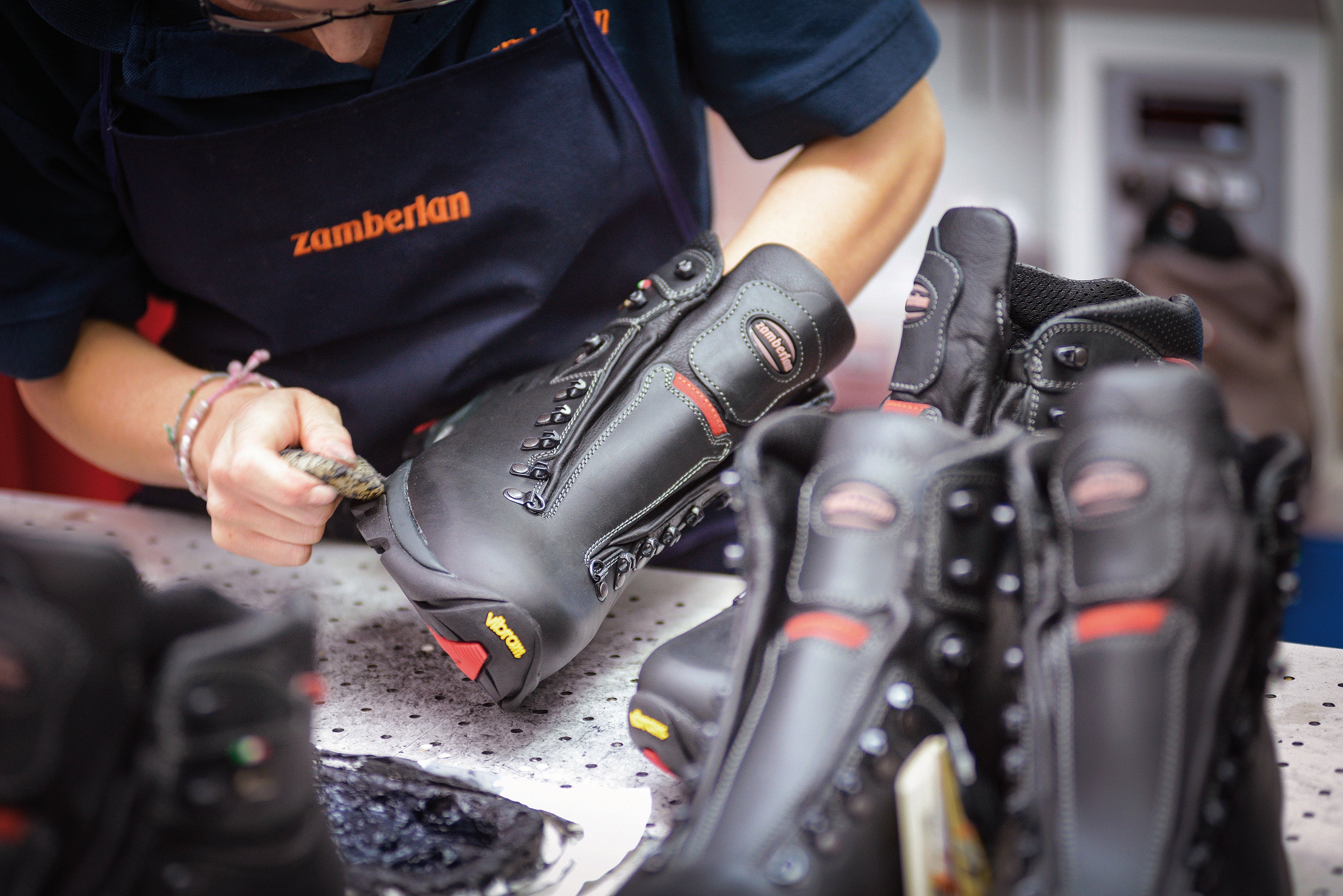 A Zamberlan factory employee polishing an unlaced Vioz GTX backpacking boot in dark grey. 