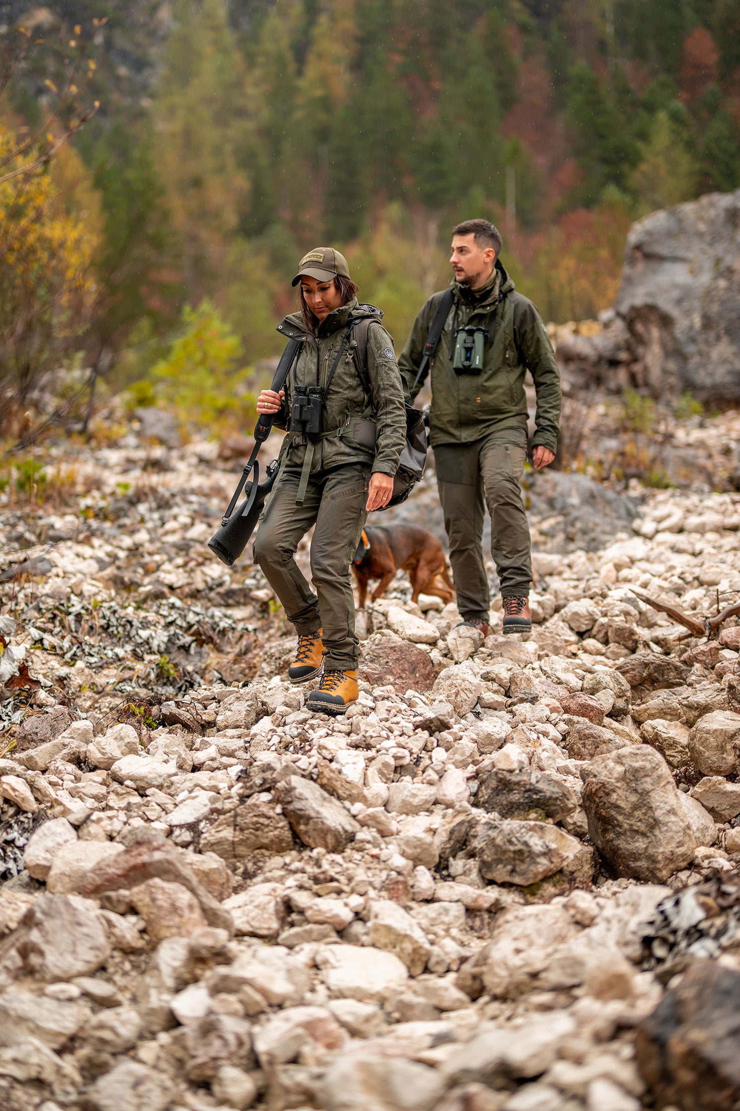 A man and a woman hiking down a rocky mountain wearing the Zamberlan Tofane GTX RR boots. 