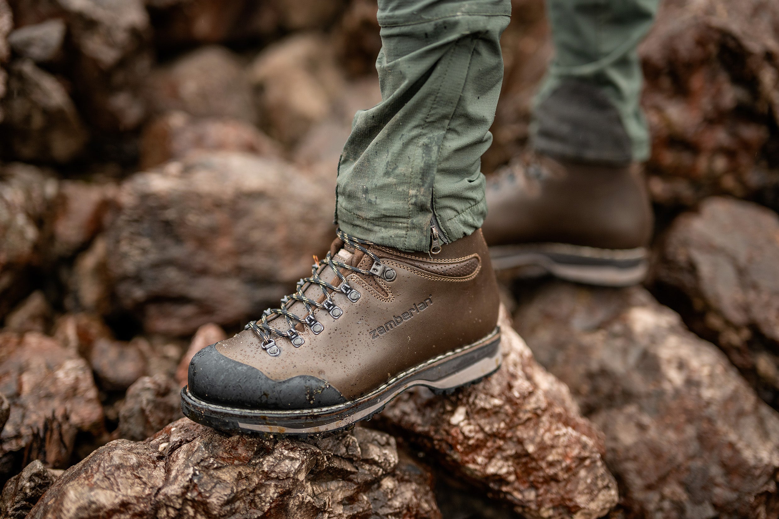A person standing on boulders wearing Zamberlan Tofane GTX RR boots. 