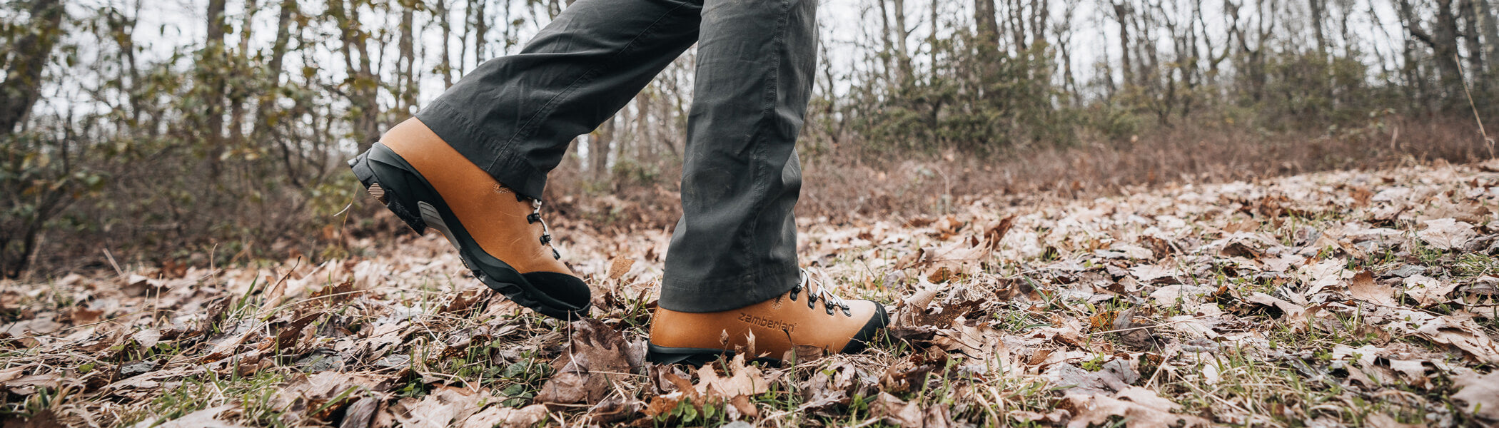 A woman wearing Vioz Luz GTX RR women's backpacking and hiking boots in camel walking through the woods. 