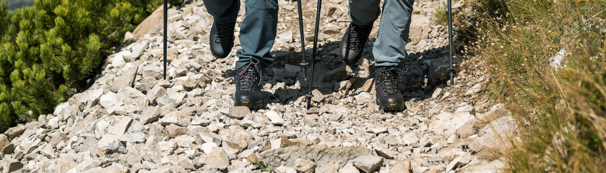 Two hikers wearing Zamberlan Vioz GTX backpacking and hiking boots hiking down a rocky path. 