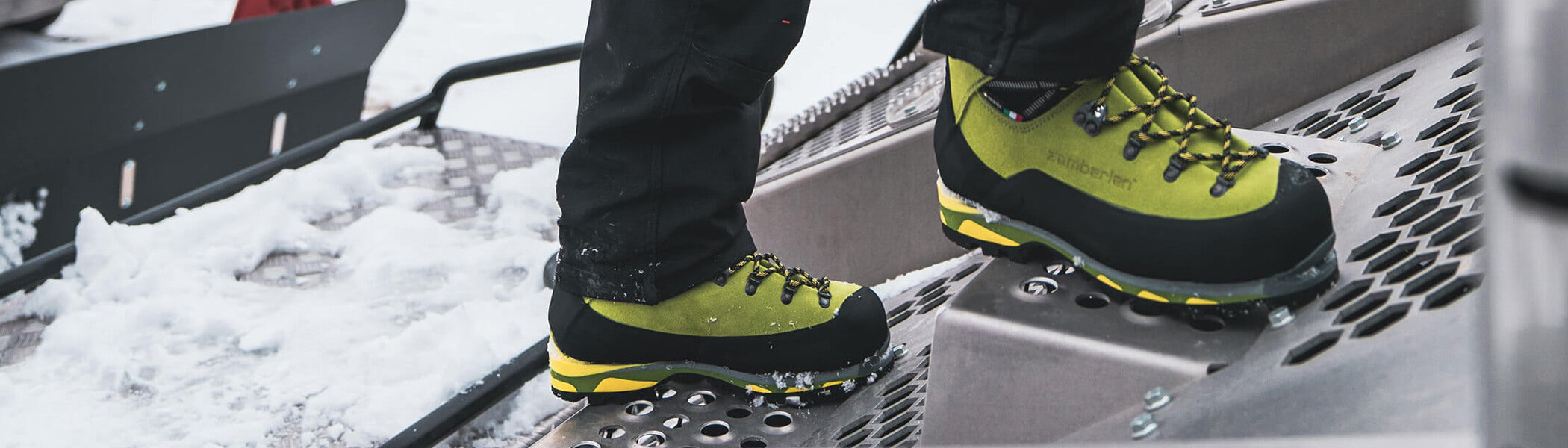 A man standing on steel steps wearing Zamberlan Mountain Lite GTX RR lineman and mountain operations boots. 