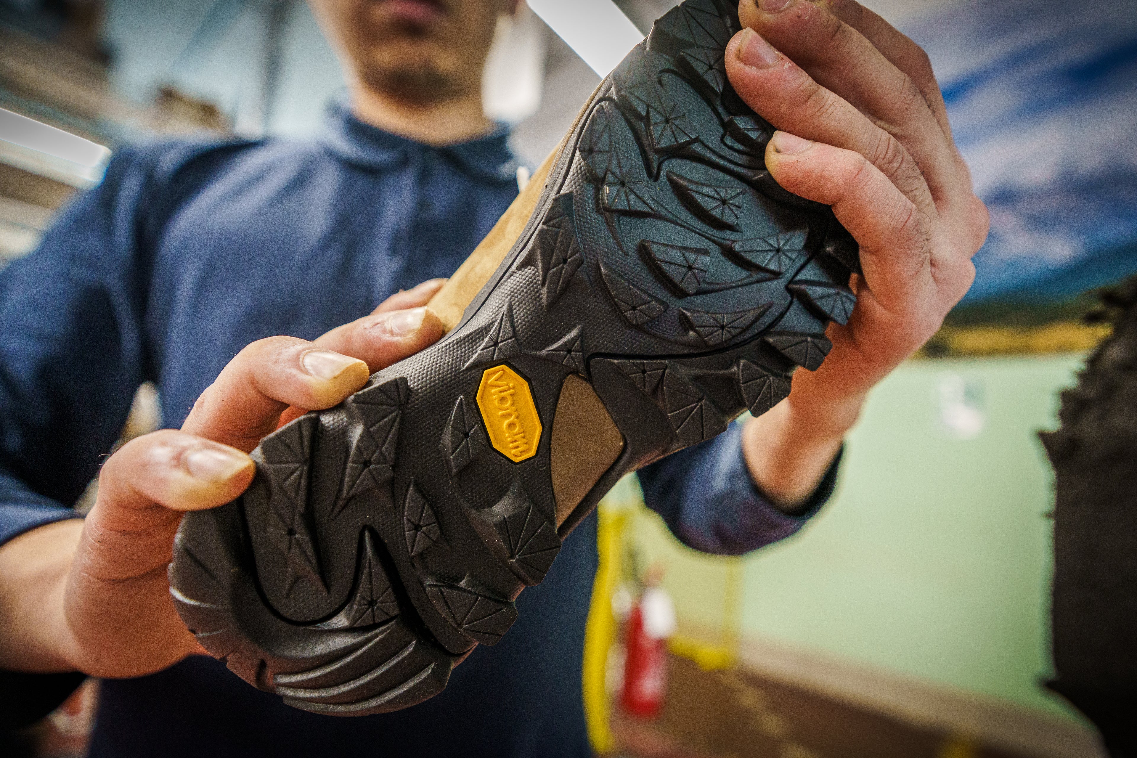 A close-up photo of a man holding a boot with a Vibram outsole.